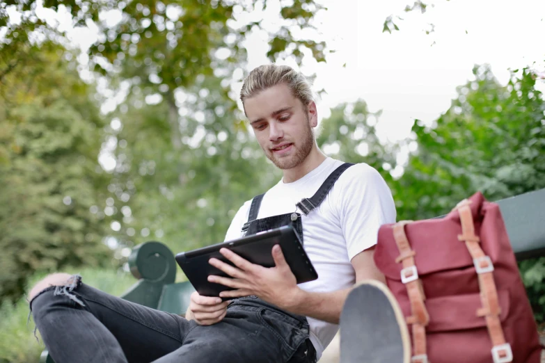 a man sits outside using a tablet computer