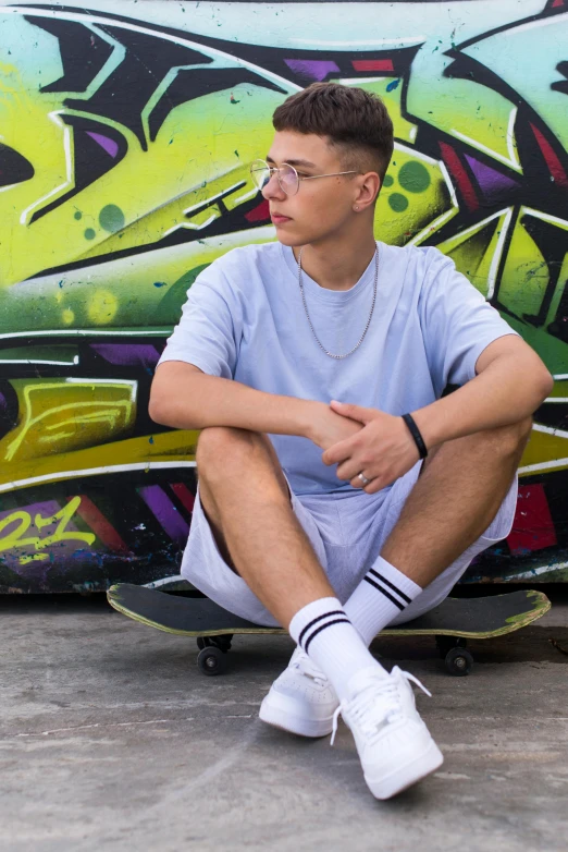 a man sitting on a skateboard in front of some graffiti