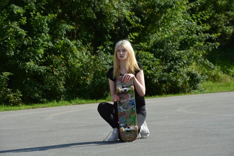 a blonde haired woman crouches on a skateboard in the road