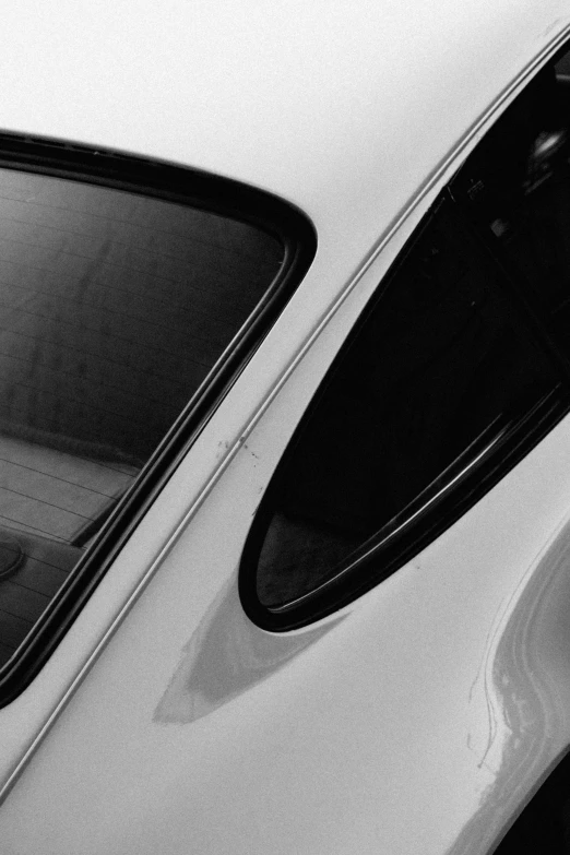 the side view of a white car parked next to a wall