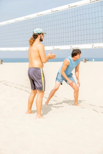 two young men standing next to each other in the sand
