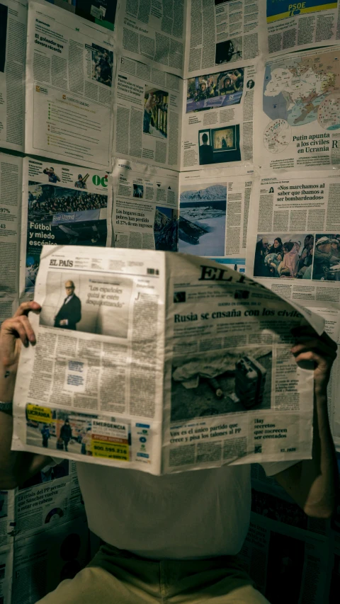 a man reading a newspaper in front of a bunch of papers