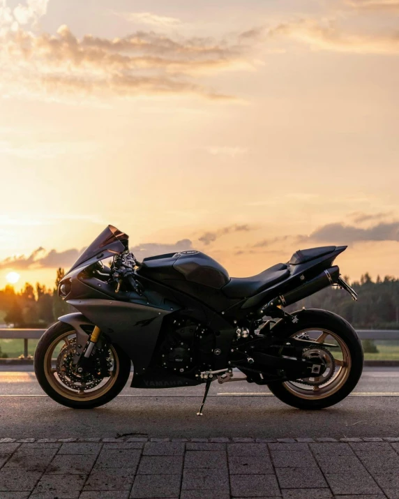 a motorcycle parked on a paved road in front of a setting sun