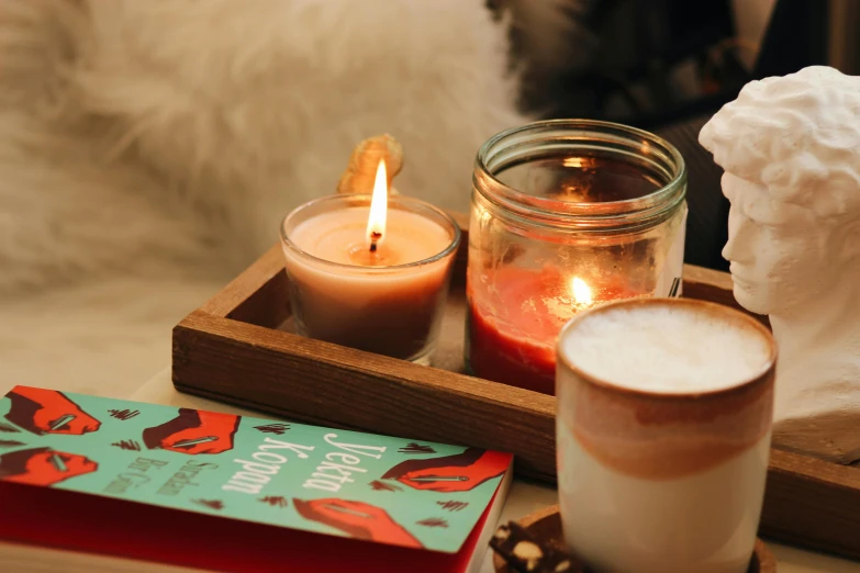 two candles on a tray and a book are on a table