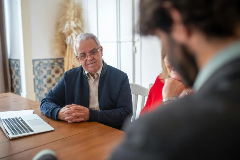 an older man with a laptop sitting at a table