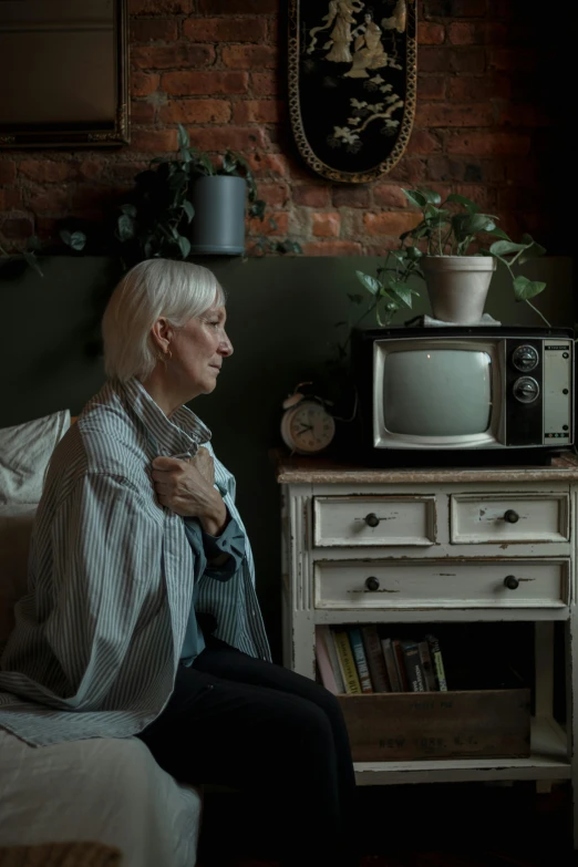 a woman sitting next to a television in a room