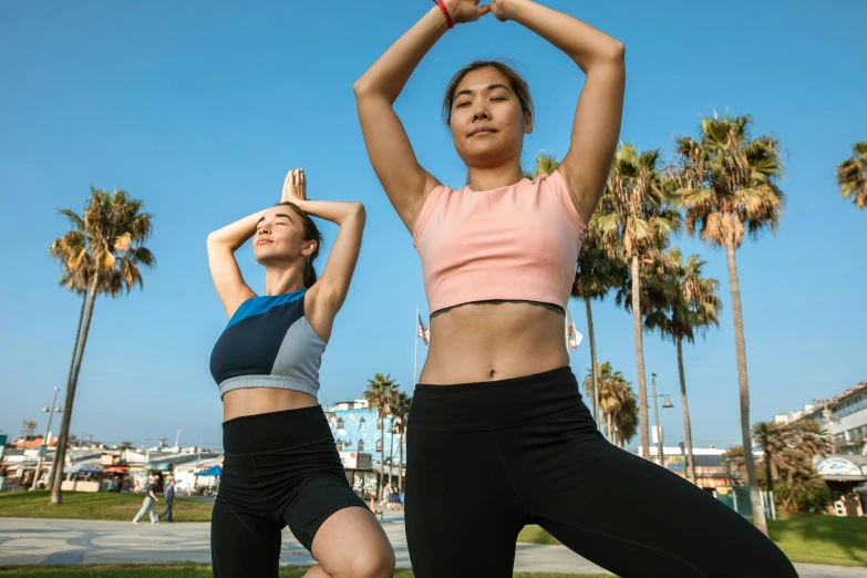 two women in yoga gear, stretching their arms with each other