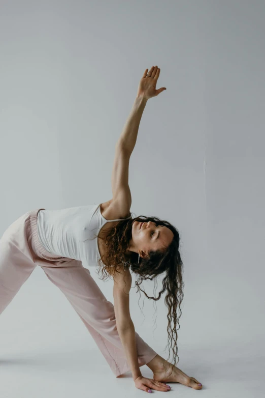 a woman wearing pink pants stretching her arm up in a yoga position