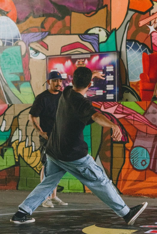 two young men walking past a colorful graffiti covered wall