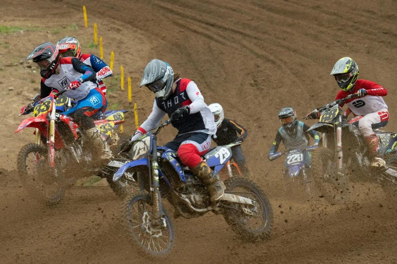 three dirt bike riders racing on muddy track