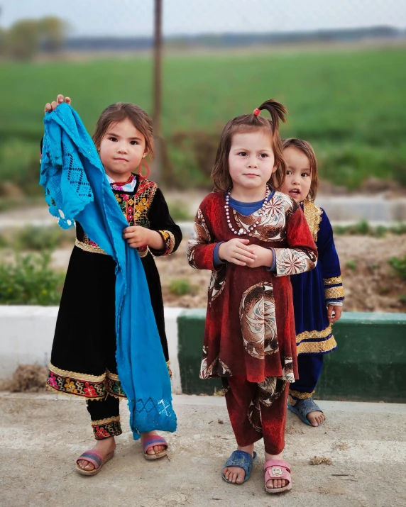 three little girls standing next to each other wearing different clothes