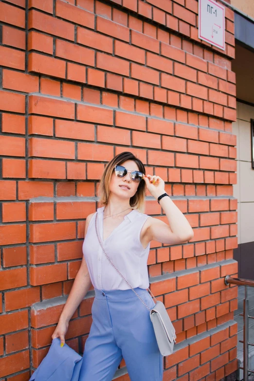 a young woman poses against a brick wall