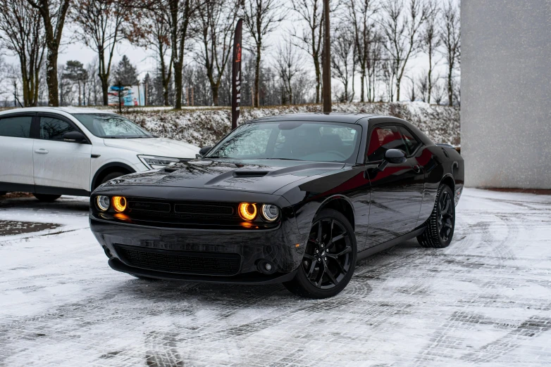 a black muscle car is parked in the snow