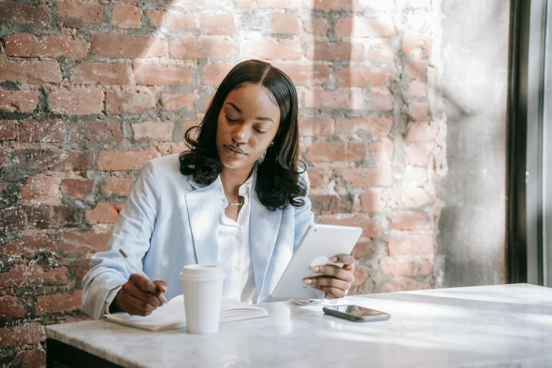 the woman is sitting at a table using a tablet