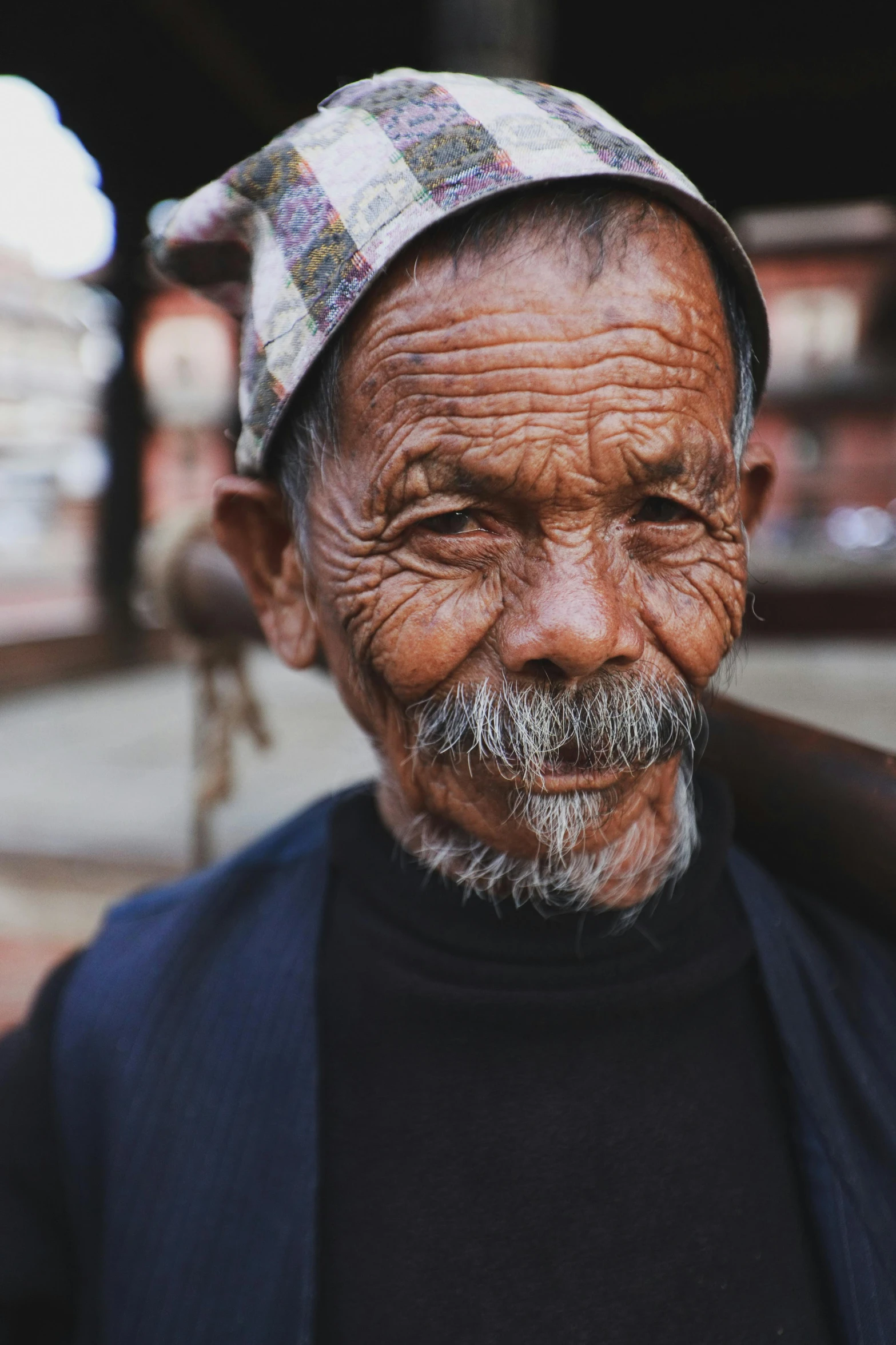 an elderly man is holding a baseball bat and wearing a patterned hat