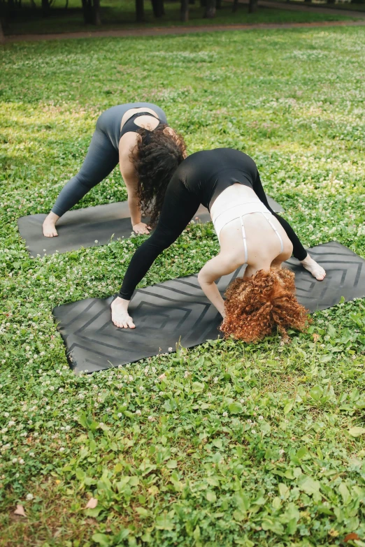 two women in black and white yoga wear doing a backbend on black mats