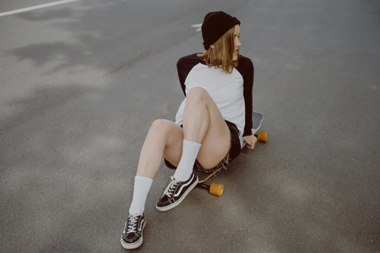 a young woman sitting on the ground on her skateboard