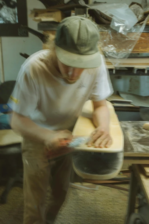 a man sanding a wooden bench in a shop