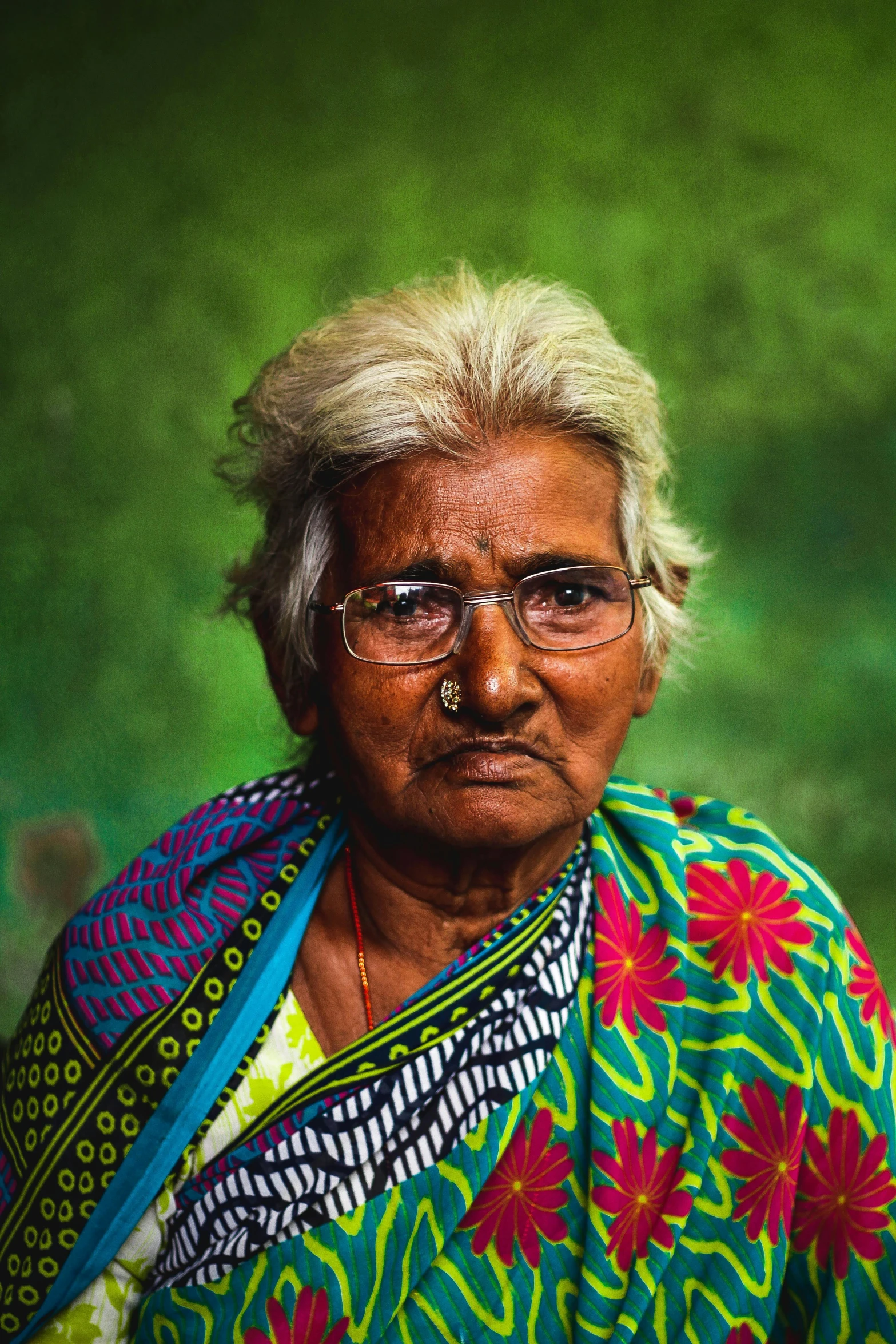 a woman with glasses, an artistic neck piece and a colorful dress