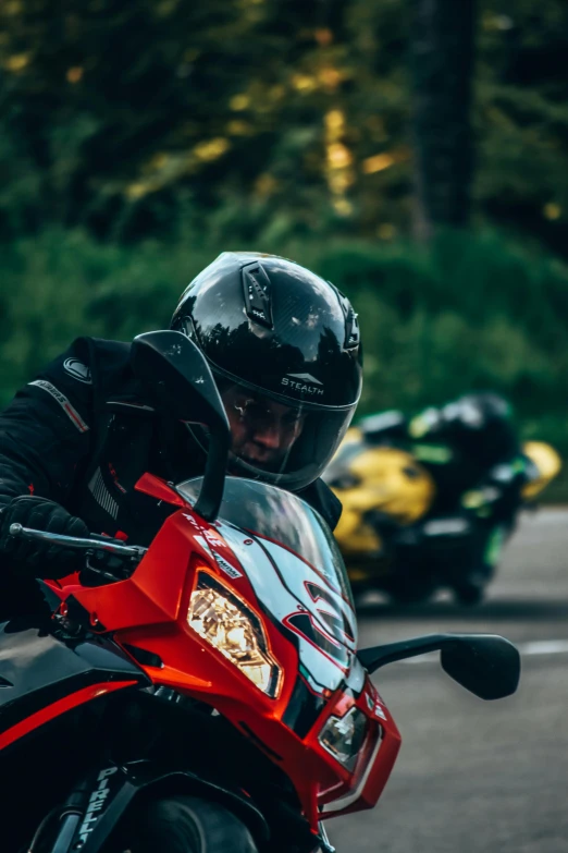 the man is riding his red motorcycle down the street