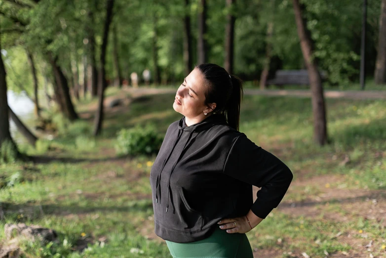 a woman standing in the woods looking up into the sky