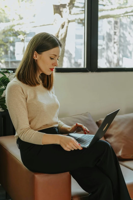 a young woman using her laptop on a sofa