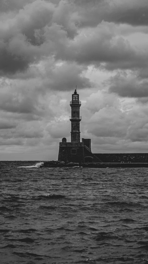 a large lighthouse sitting on the water under cloudy skies