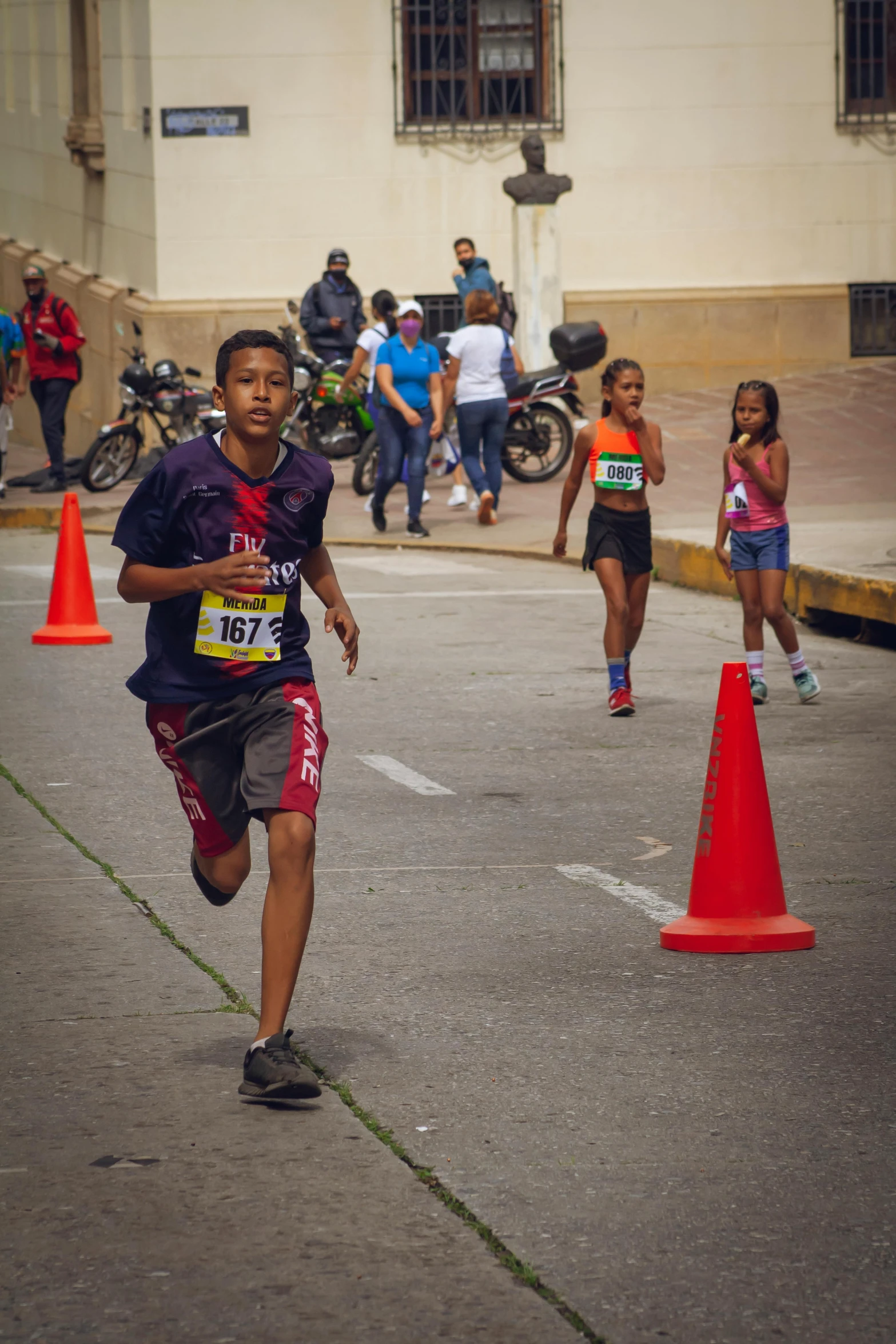 a young child running through an open parking lot with some orange cones