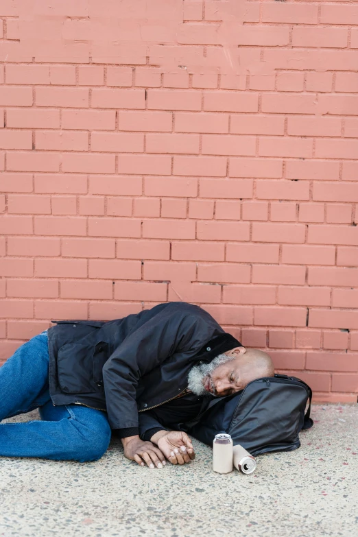 a person with a backpack and drink is sleeping on the ground