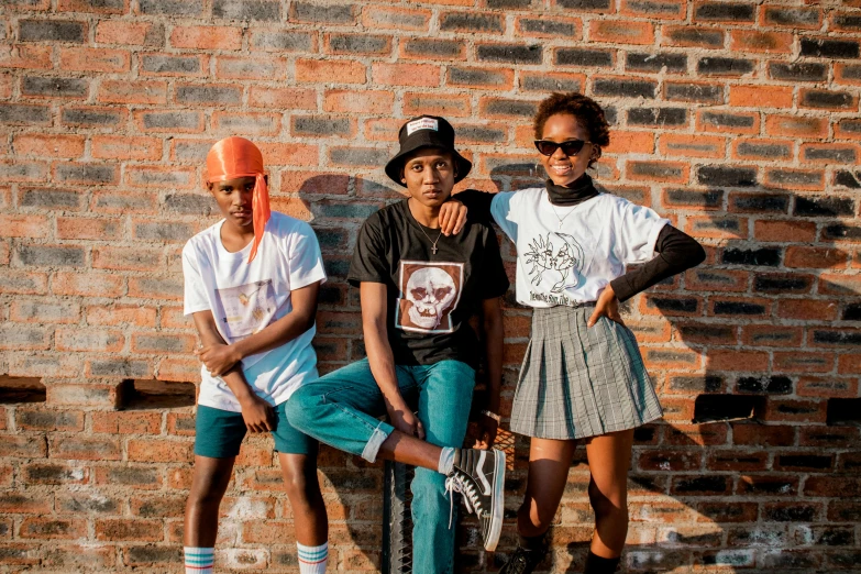 three young children standing against a brick wall