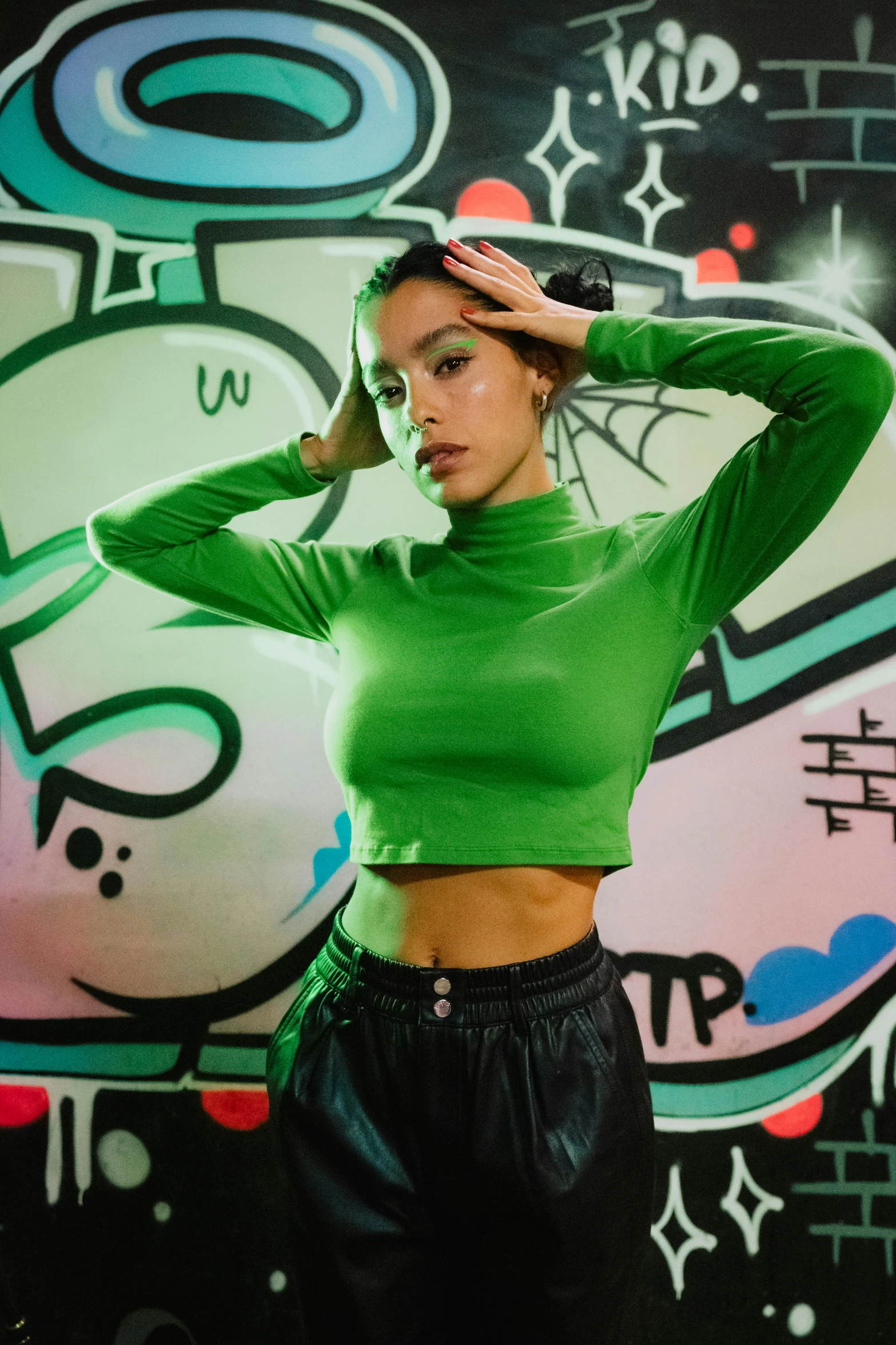 a beautiful young woman standing in front of a wall