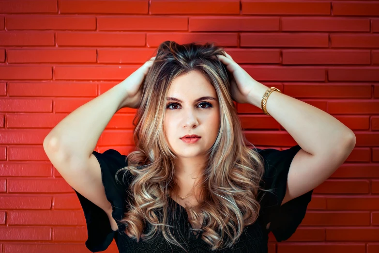 an attractive young woman stands against a brick wall