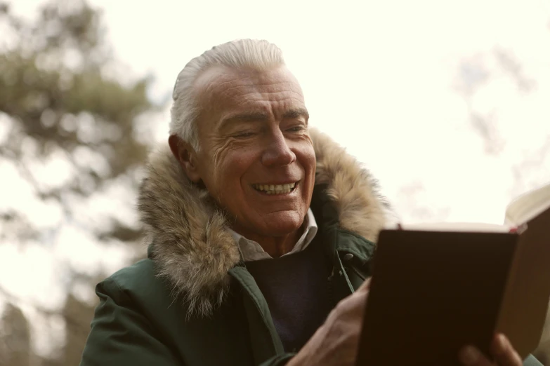 the elderly man is smiling while looking at a book