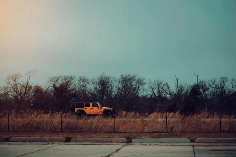 a yellow truck is parked in front of some brown grass