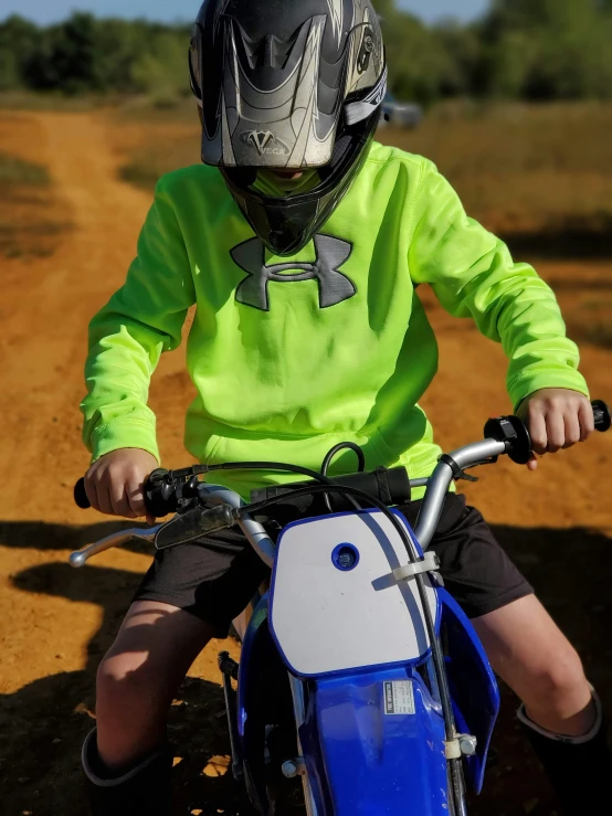 a little boy riding on the back of a dirt bike