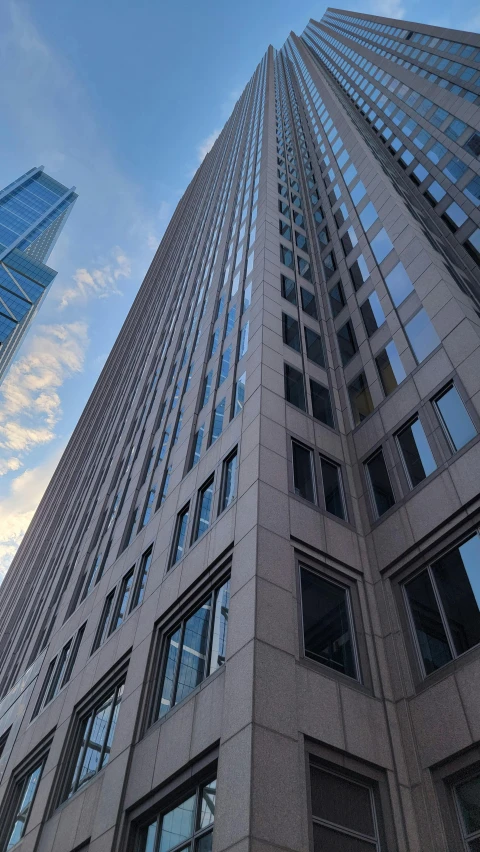 the tall skyscr with many windows is next to another very big building