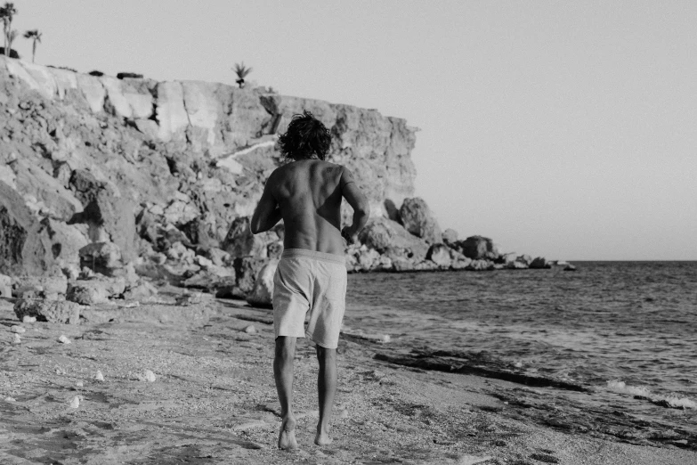 the man is walking on the beach next to the water