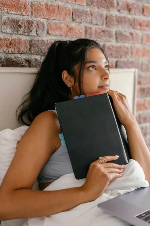 a woman is sitting in bed and holding a book over her head