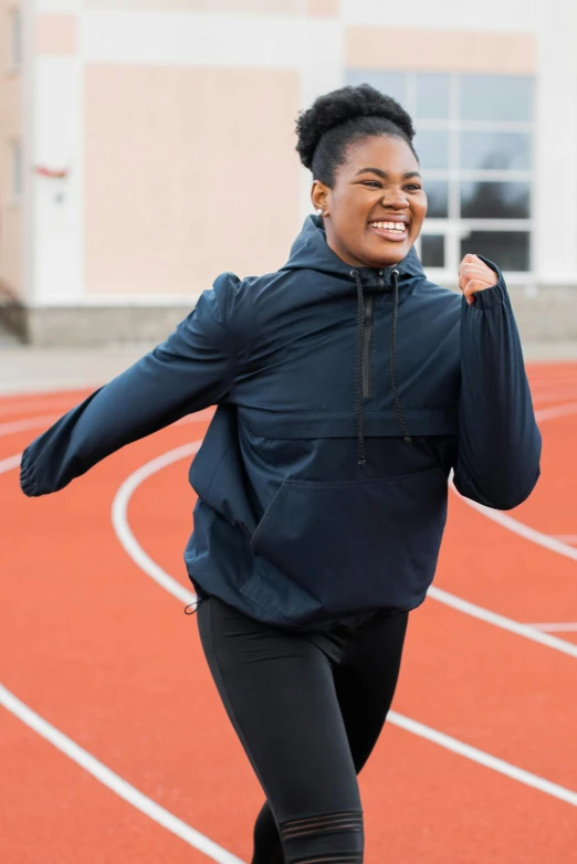 the woman smiles as she runs on a track