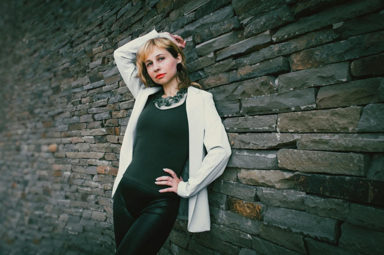 a young woman leans against a wall