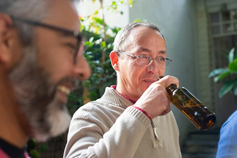 a man standing next to another man holding a bottle