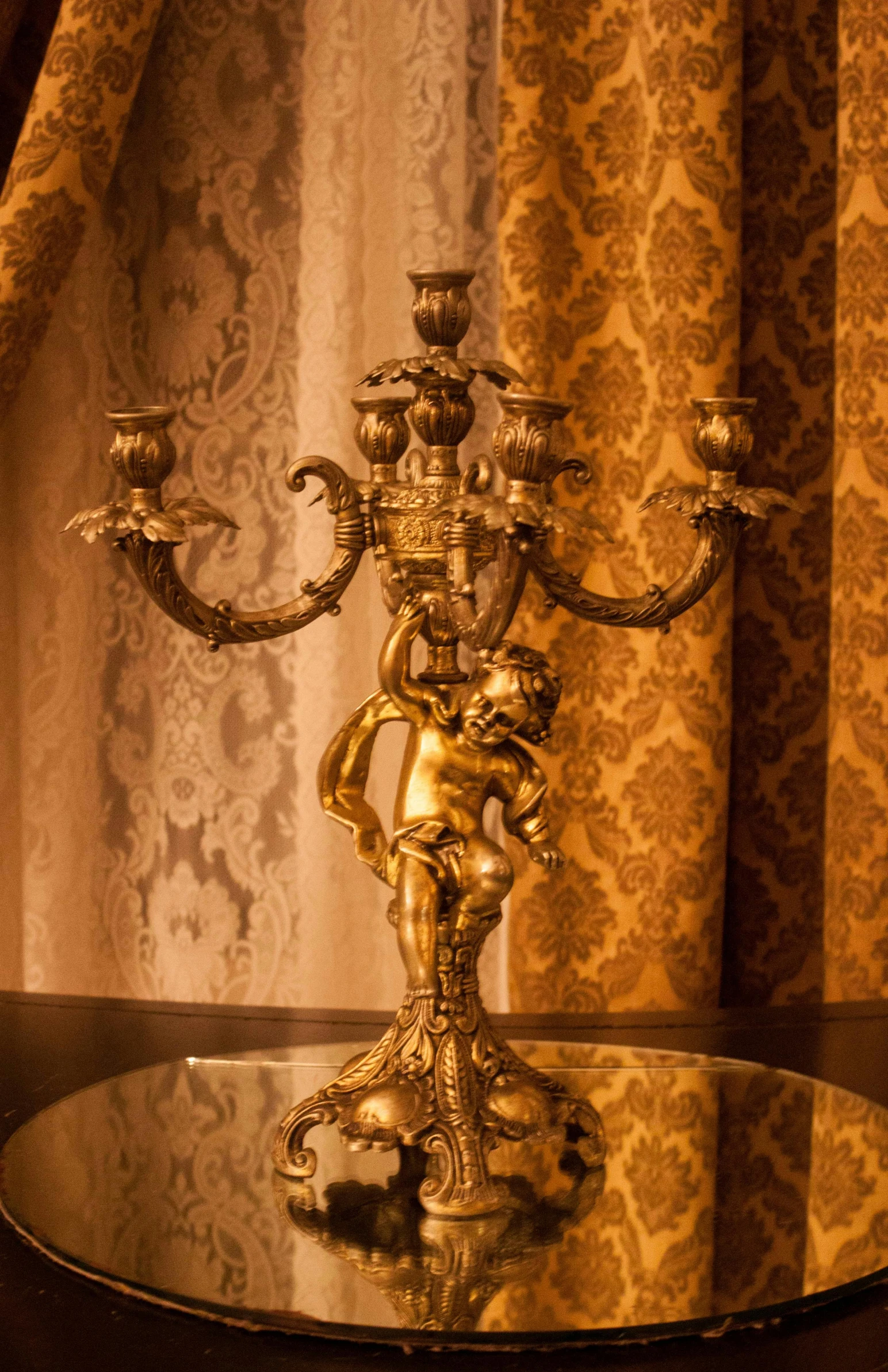 a golden candle holder is sitting on top of the table