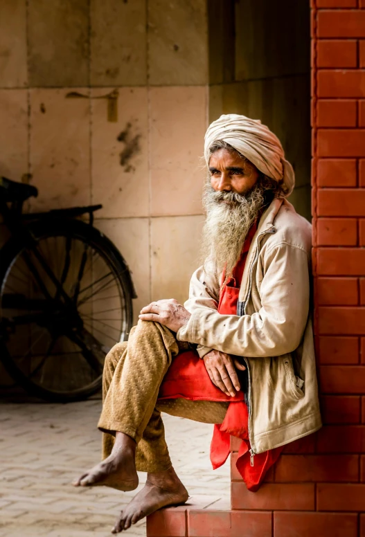 a bearded man sitting on a red brick wall