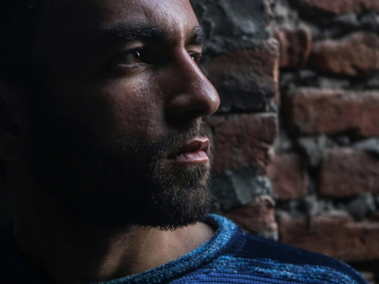 the head of a man in blue shirt and brick wall