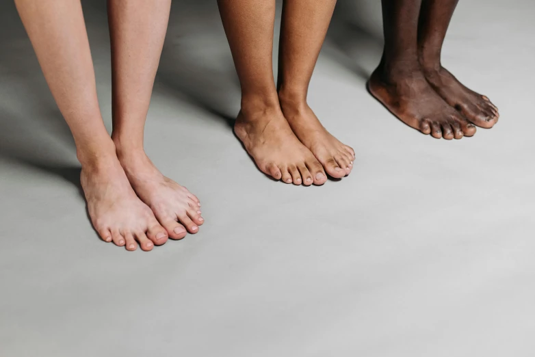 three people standing side by side with their bare feet crossed