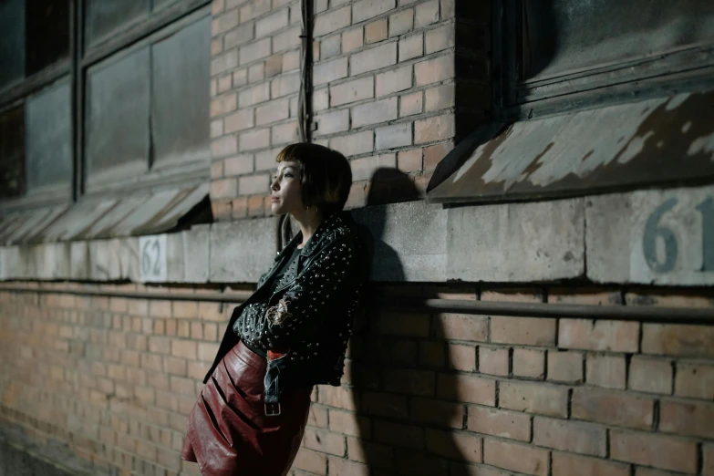 a woman leaning up against a brick wall