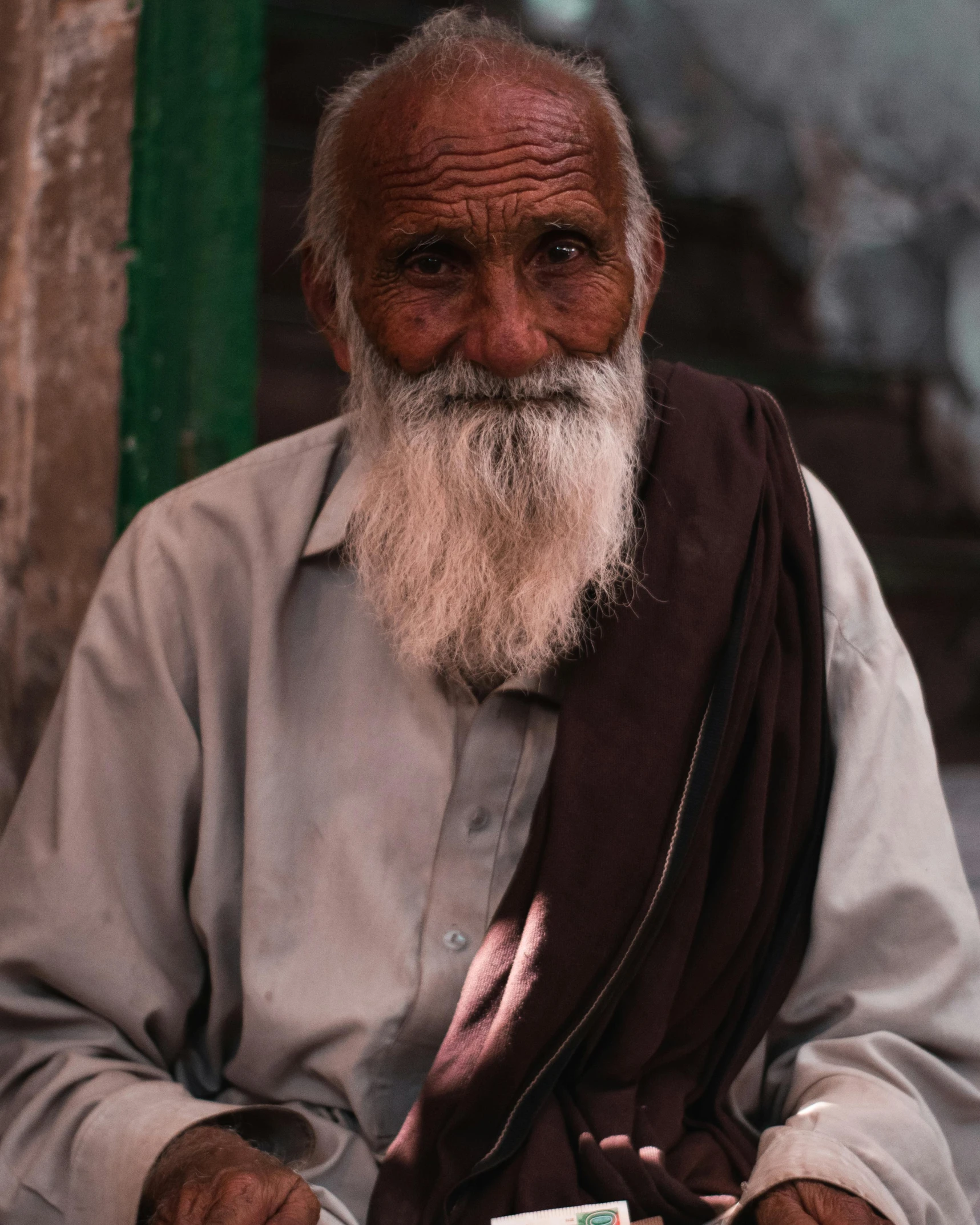 old indian man sits down looking directly at the camera