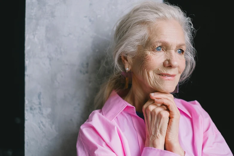 an elderly woman wearing a pink shirt posing for the camera