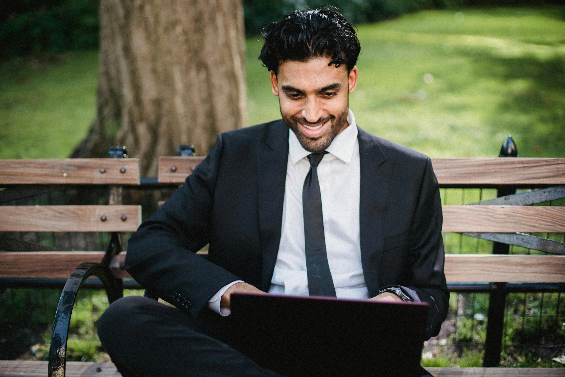 a man in a suit sitting on a bench and smiling