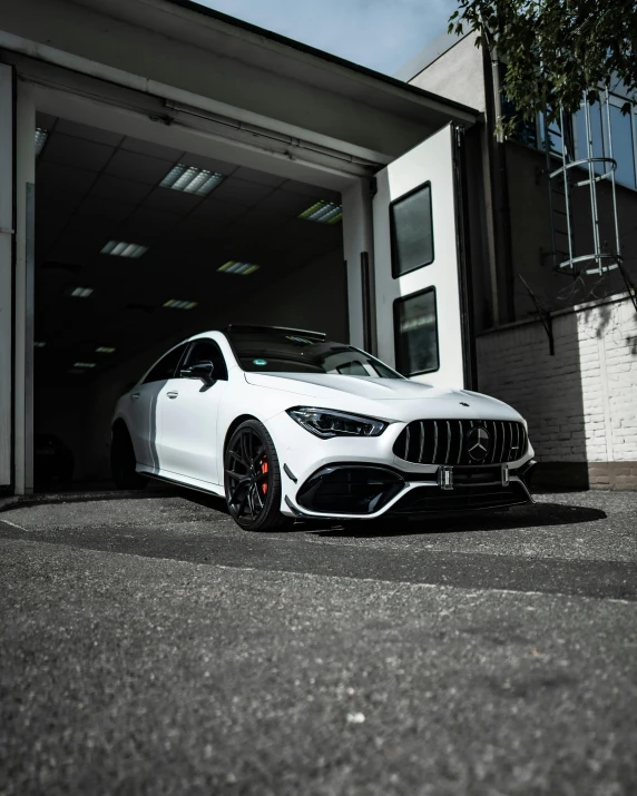 the white car is parked in front of an open garage door